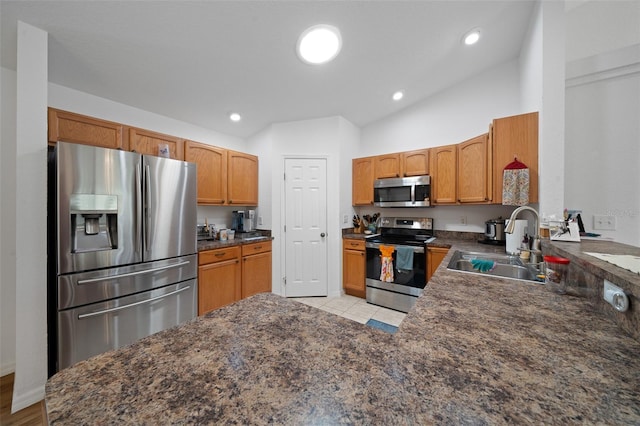 kitchen with brown cabinets, stainless steel appliances, lofted ceiling, recessed lighting, and a sink