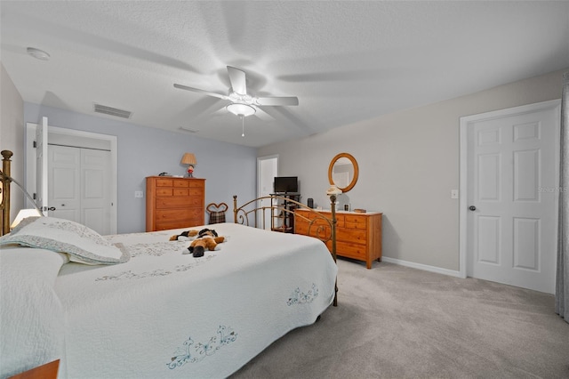 bedroom featuring light colored carpet, visible vents, ceiling fan, a textured ceiling, and baseboards