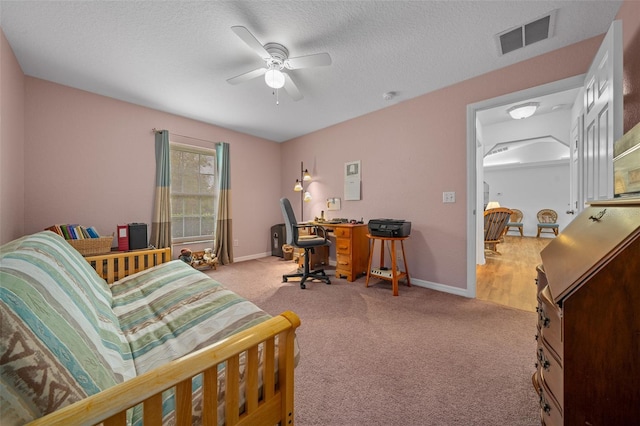 carpeted home office featuring a ceiling fan, visible vents, a textured ceiling, and baseboards