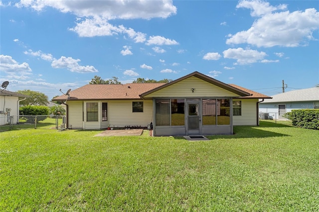 back of house featuring a sunroom, a lawn, and a fenced backyard