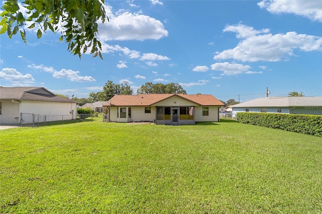 rear view of property featuring a lawn, fence, and a sunroom