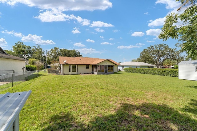 rear view of house with a sunroom, a storage shed, a fenced backyard, an outdoor structure, and a yard