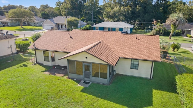 rear view of house with a residential view, a lawn, fence, and a sunroom