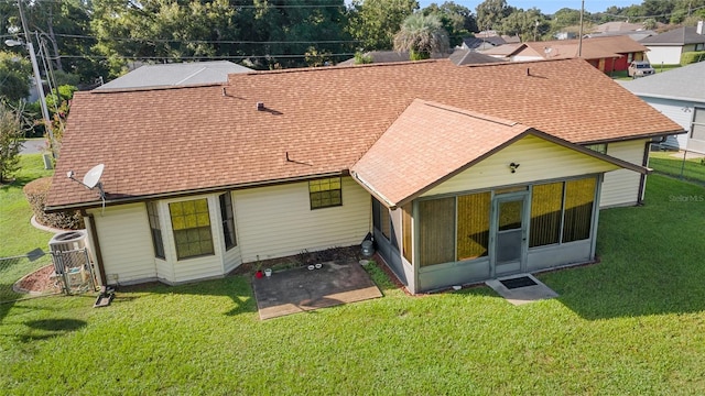 back of house with a patio, a yard, a sunroom, and roof with shingles