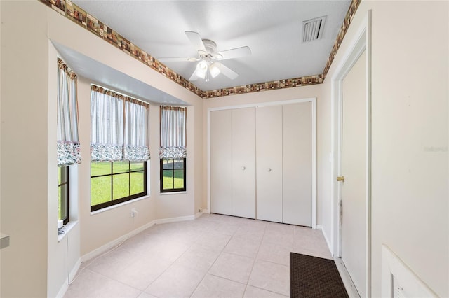 unfurnished bedroom with visible vents, a ceiling fan, a closet, light tile patterned flooring, and baseboards