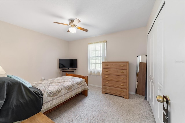 bedroom with a closet, light carpet, baseboards, and a ceiling fan