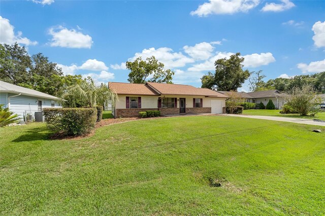 single story home with a garage, a front yard, brick siding, and driveway