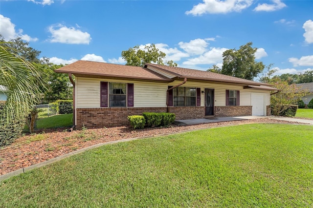 single story home featuring brick siding, fence, a front yard, a garage, and driveway