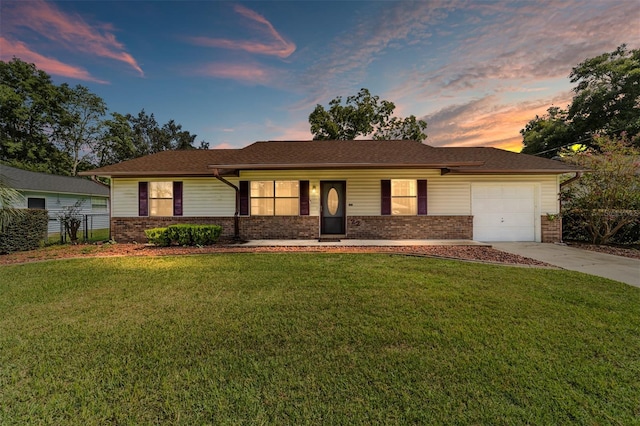 ranch-style home featuring brick siding, a garage, a front lawn, and driveway