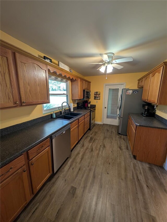 kitchen featuring dark countertops, dark wood-style flooring, appliances with stainless steel finishes, and a sink