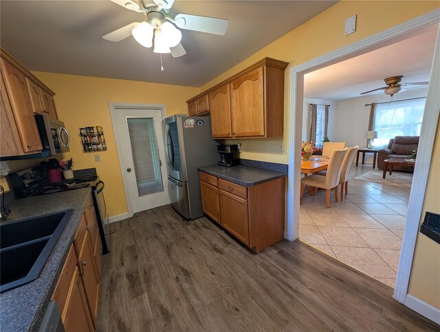 kitchen featuring stainless steel appliances, dark wood-type flooring, dark countertops, and brown cabinetry