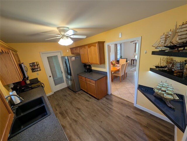 kitchen featuring ceiling fan, dark wood finished floors, brown cabinets, freestanding refrigerator, and a sink