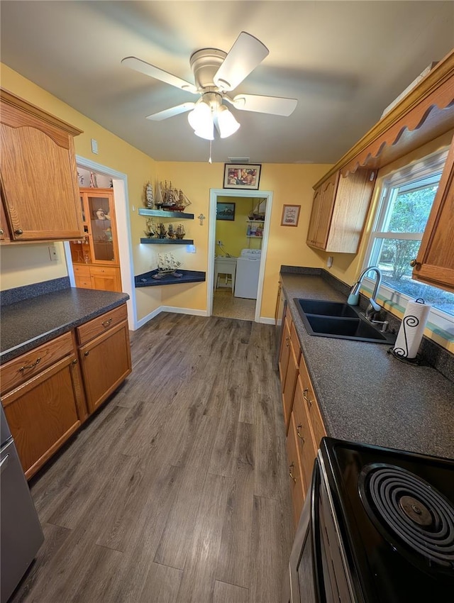 kitchen featuring dark countertops, black electric range, dark wood-style flooring, and a sink