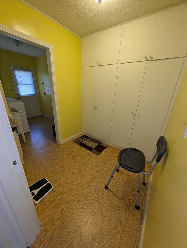 interior space with light wood-style floors, baseboards, and a textured ceiling