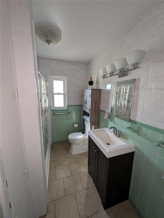 full bath featuring curtained shower, toilet, vanity, tile patterned floors, and tile walls