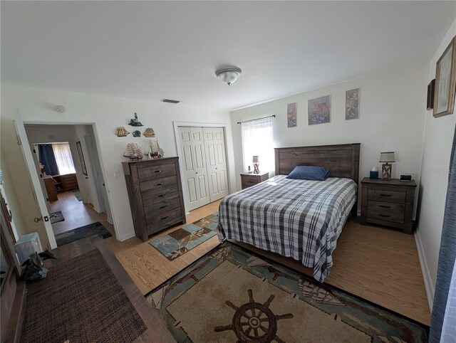 bedroom featuring a closet, visible vents, multiple windows, and wood finished floors