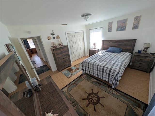 bedroom with wood finished floors, a closet, and baseboards