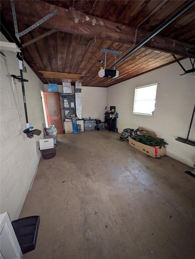 garage with concrete block wall, a garage door opener, and wooden ceiling