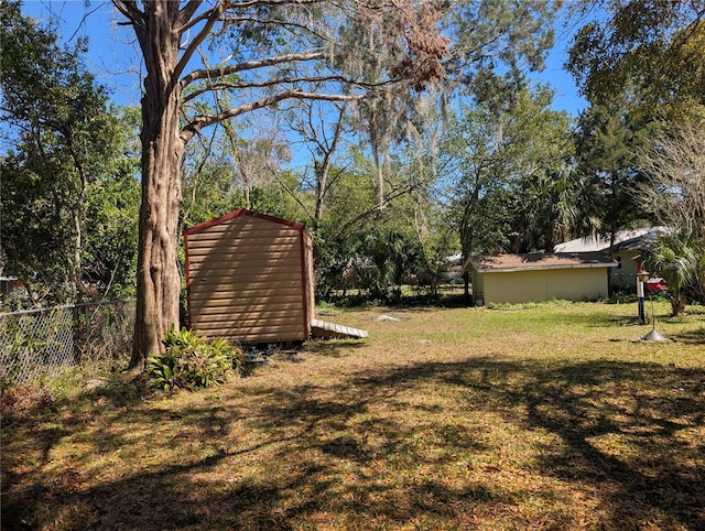 view of yard featuring a storage shed, an outdoor structure, and fence