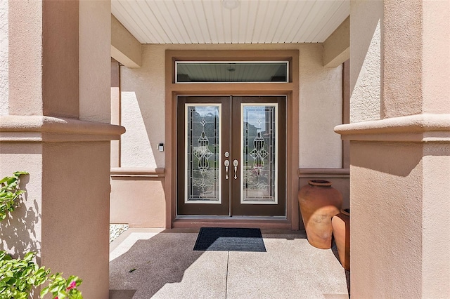 view of exterior entry featuring stucco siding and french doors