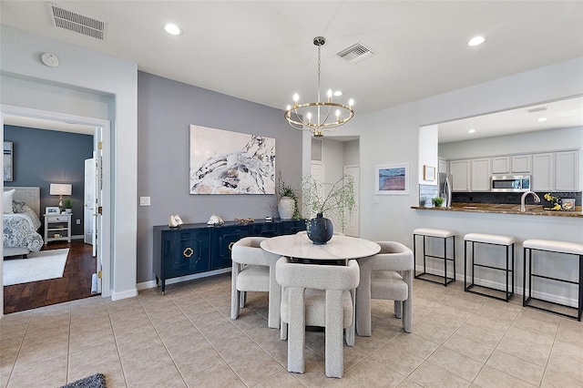 dining room with light tile patterned floors, visible vents, baseboards, and an inviting chandelier