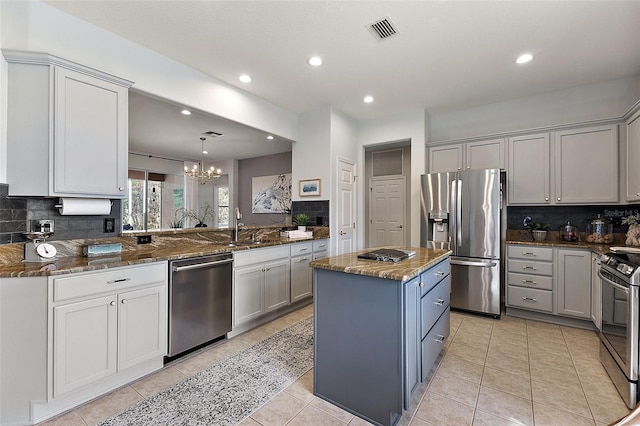 kitchen with dark stone countertops, light tile patterned floors, visible vents, stainless steel appliances, and a center island