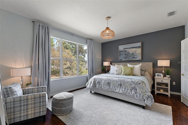 bedroom with visible vents, a textured ceiling, baseboards, and hardwood / wood-style floors