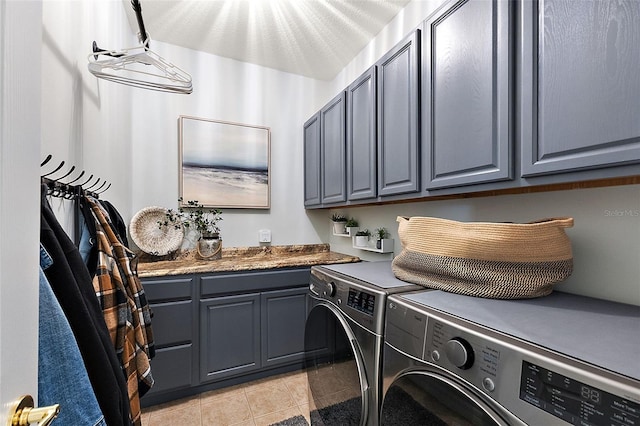 laundry area featuring washer and dryer, light tile patterned flooring, and cabinet space