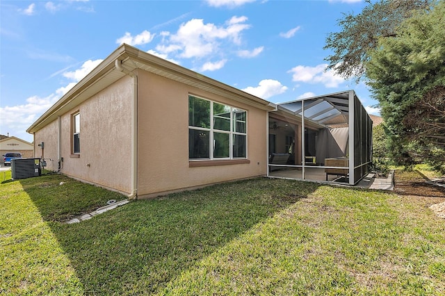 view of side of property with a yard, central air condition unit, glass enclosure, and stucco siding