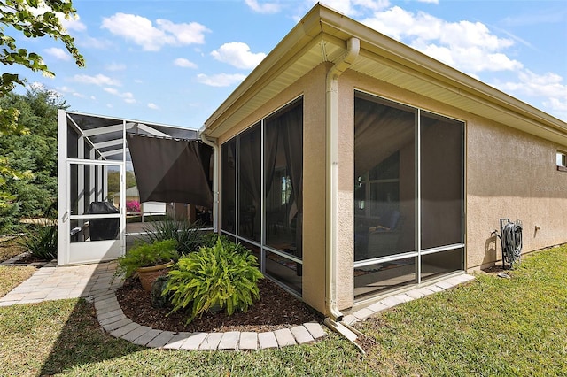 view of property exterior featuring a lanai, a lawn, and stucco siding