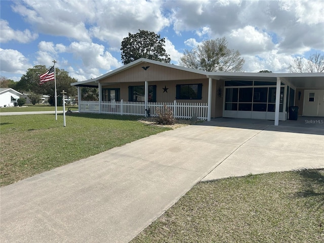 view of front of property featuring concrete driveway, fence, a front lawn, and a carport