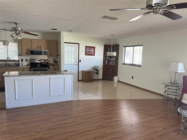 kitchen with visible vents, light wood-type flooring, appliances with stainless steel finishes, a textured ceiling, and a sink