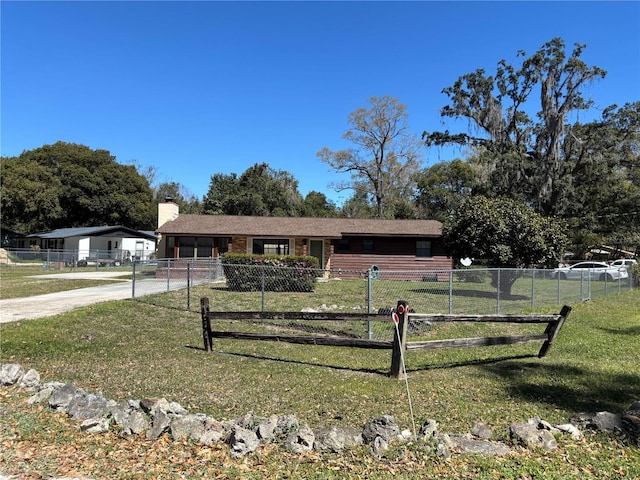 ranch-style home featuring a chimney, driveway, a fenced front yard, and a front yard