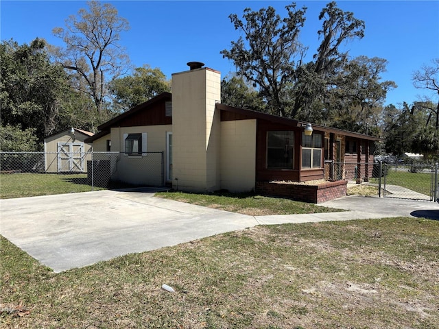 view of side of property with a storage shed, a lawn, concrete block siding, an outbuilding, and fence