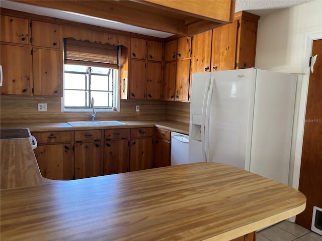 kitchen with light countertops, white appliances, brown cabinetry, and a sink