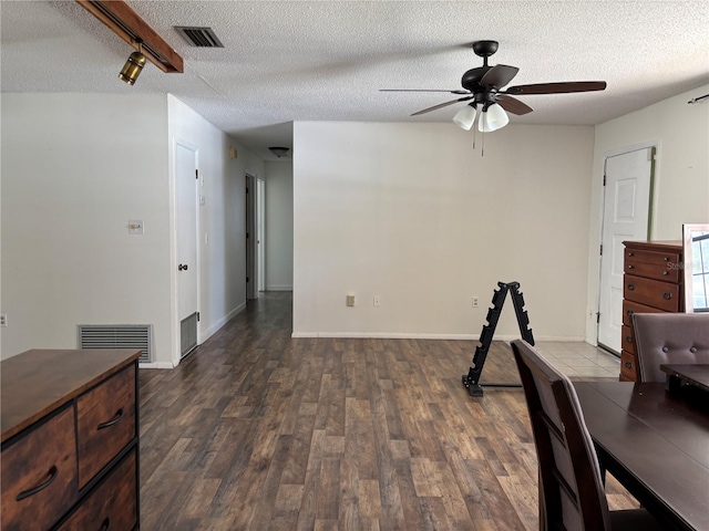 interior space with a textured ceiling, dark wood-style flooring, and visible vents