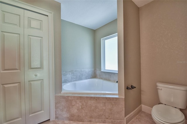 full bathroom featuring a closet, toilet, a bath, baseboards, and tile patterned floors