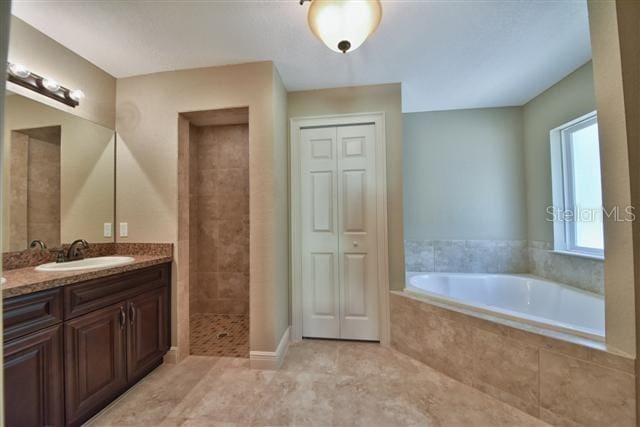 full bath with tiled shower, tile patterned floors, a garden tub, vanity, and a closet