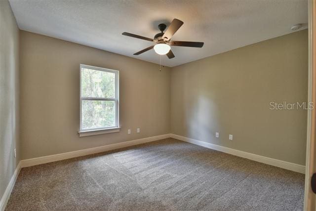 empty room with carpet, baseboards, and a ceiling fan