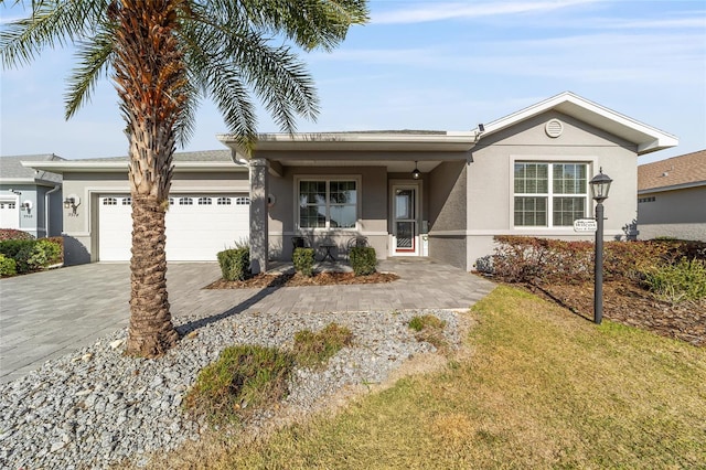 ranch-style home with a front lawn, decorative driveway, an attached garage, and stucco siding