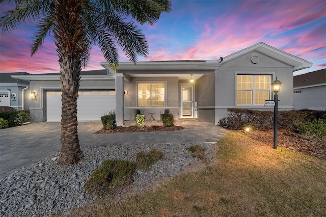 single story home with stucco siding, decorative driveway, and a garage