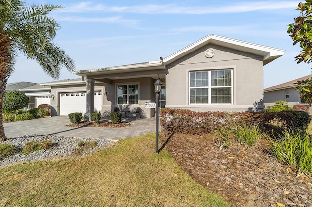 single story home featuring decorative driveway, an attached garage, and stucco siding