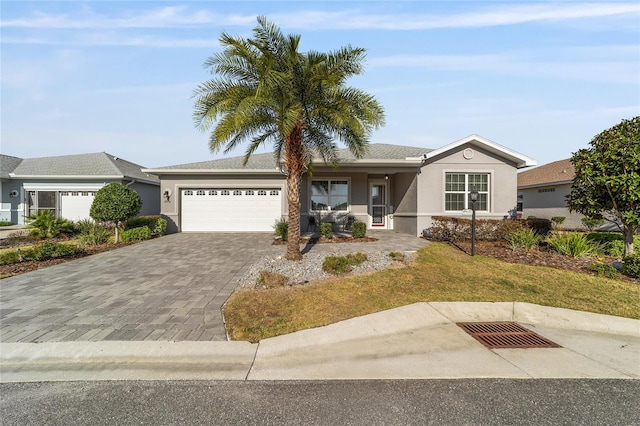 ranch-style house featuring decorative driveway, an attached garage, and stucco siding