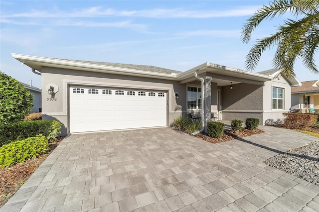 ranch-style house with decorative driveway, an attached garage, and stucco siding