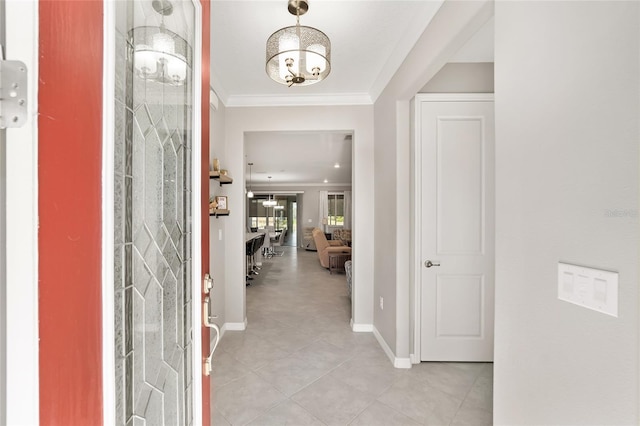 entrance foyer featuring light tile patterned floors, baseboards, a chandelier, and crown molding