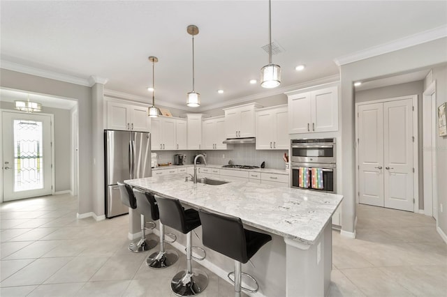 kitchen featuring crown molding, backsplash, appliances with stainless steel finishes, and a sink