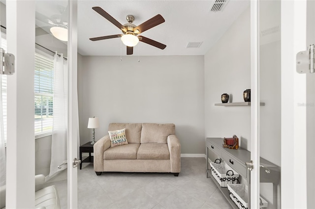 living room featuring light tile patterned floors, visible vents, and a ceiling fan