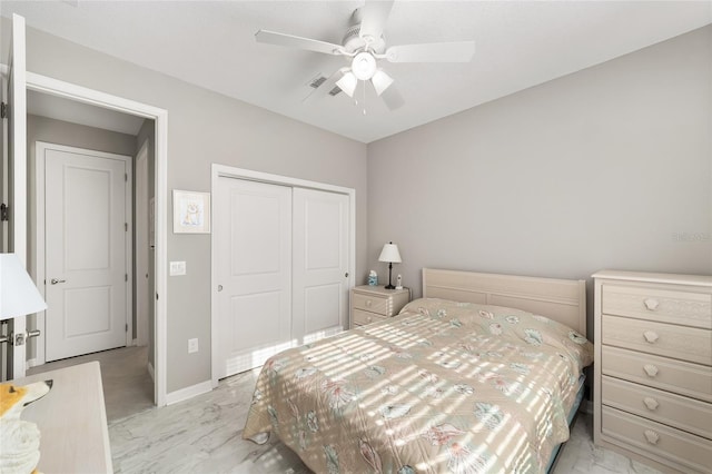 bedroom with a closet, marble finish floor, baseboards, and ceiling fan