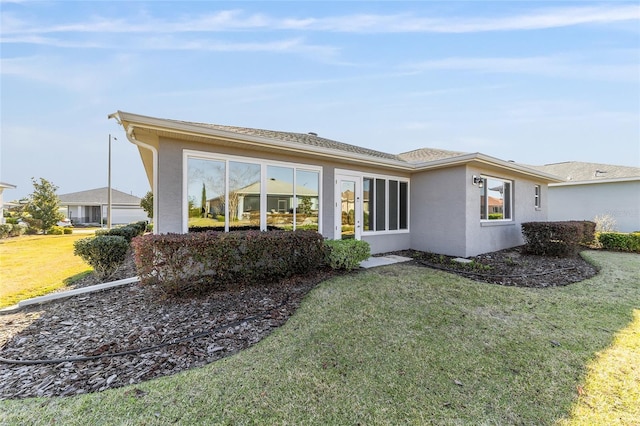 back of property with a lawn and stucco siding