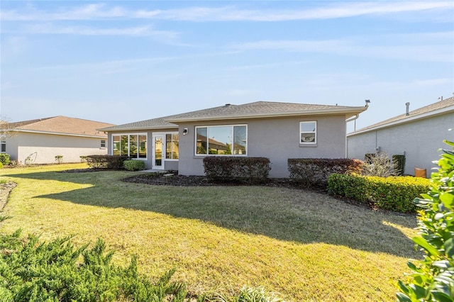 rear view of property featuring a lawn and stucco siding